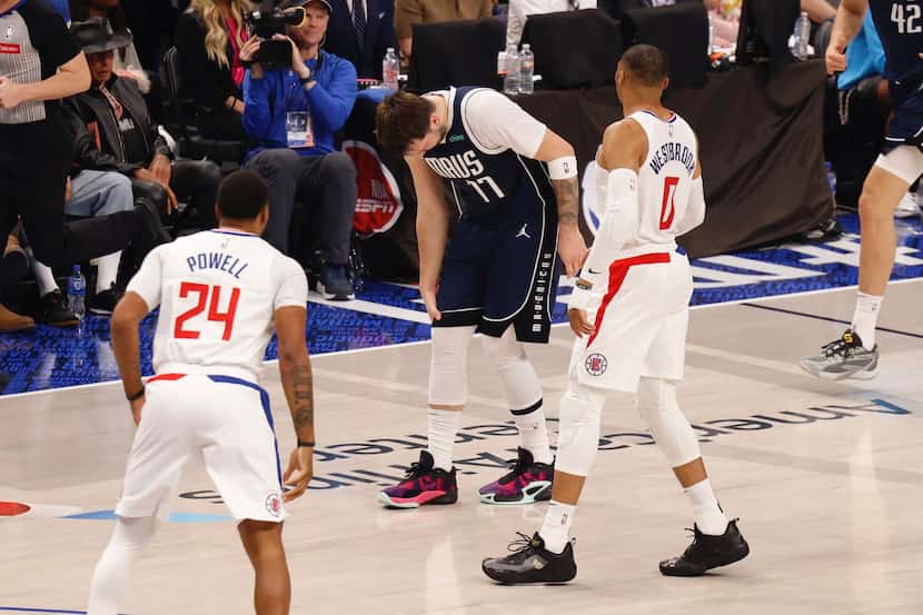 Luka Doncic grabs at his right knee after a fall during Game 3 of an NBA basketball...