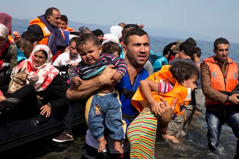 
In this September  photo, Syrian refugees arrive aboard a dinghy after crossing from Turkey...