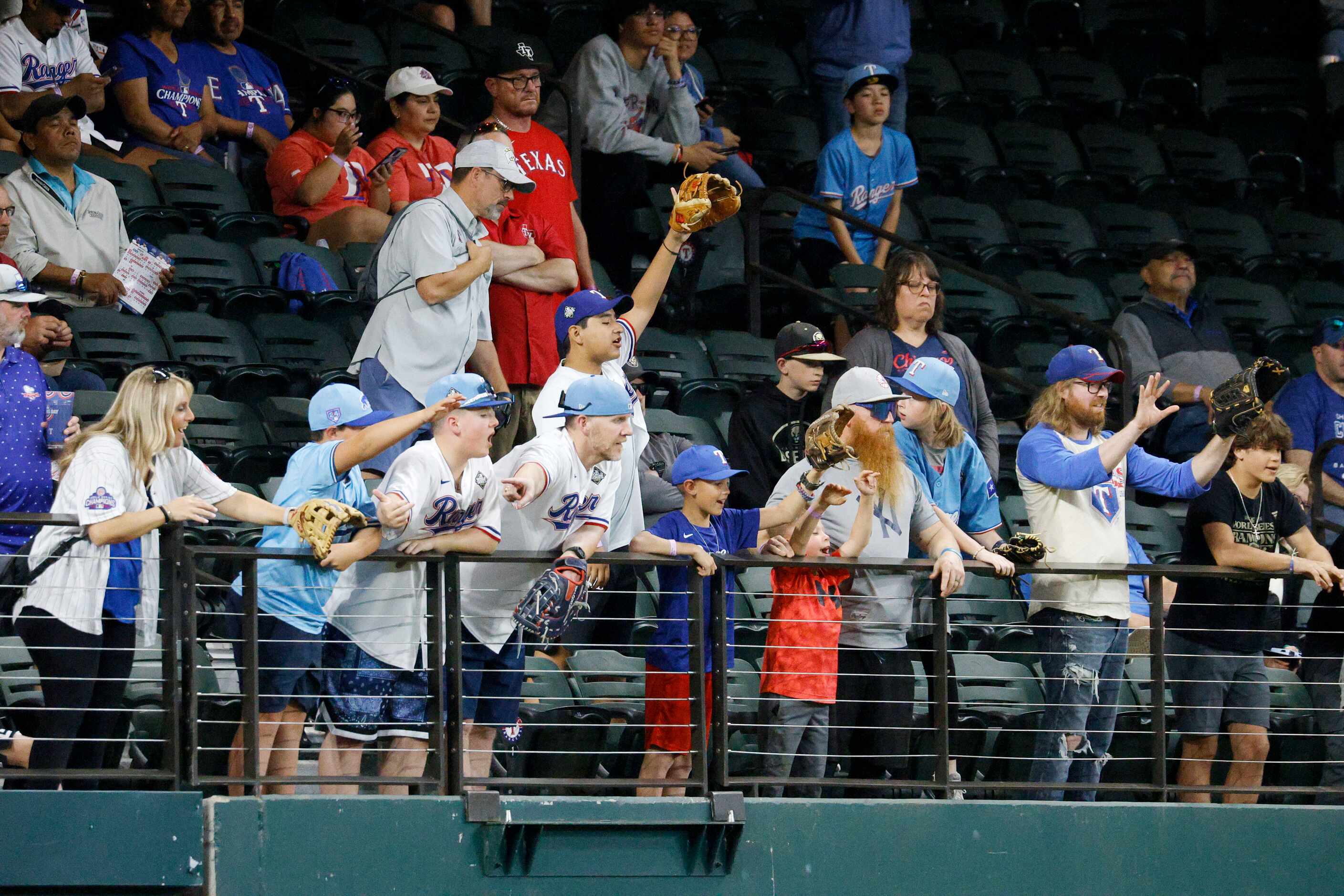 Fans try to reach for a ball tossed into the stands as they watch the Chicago Cubs take...