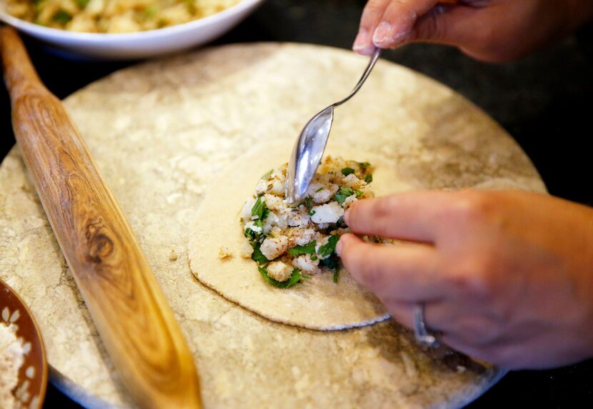 Sapna Punjabi-Gupta places potato filling on dough in preparation of making a paratha.