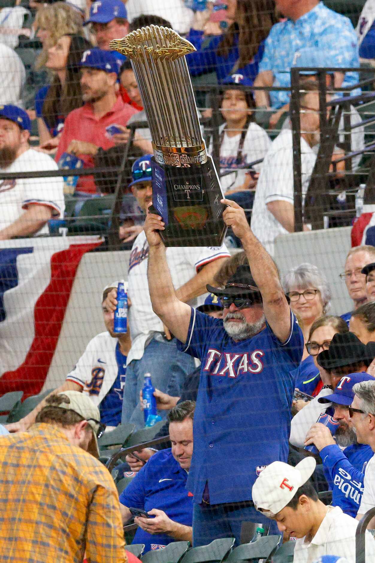 A Texas Rangers fan holds up a World Series championship trophy before the season opener at...