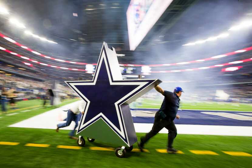 Dallas Cowboys workers rush one of the pregame pyrotechnics off the field before the opening...