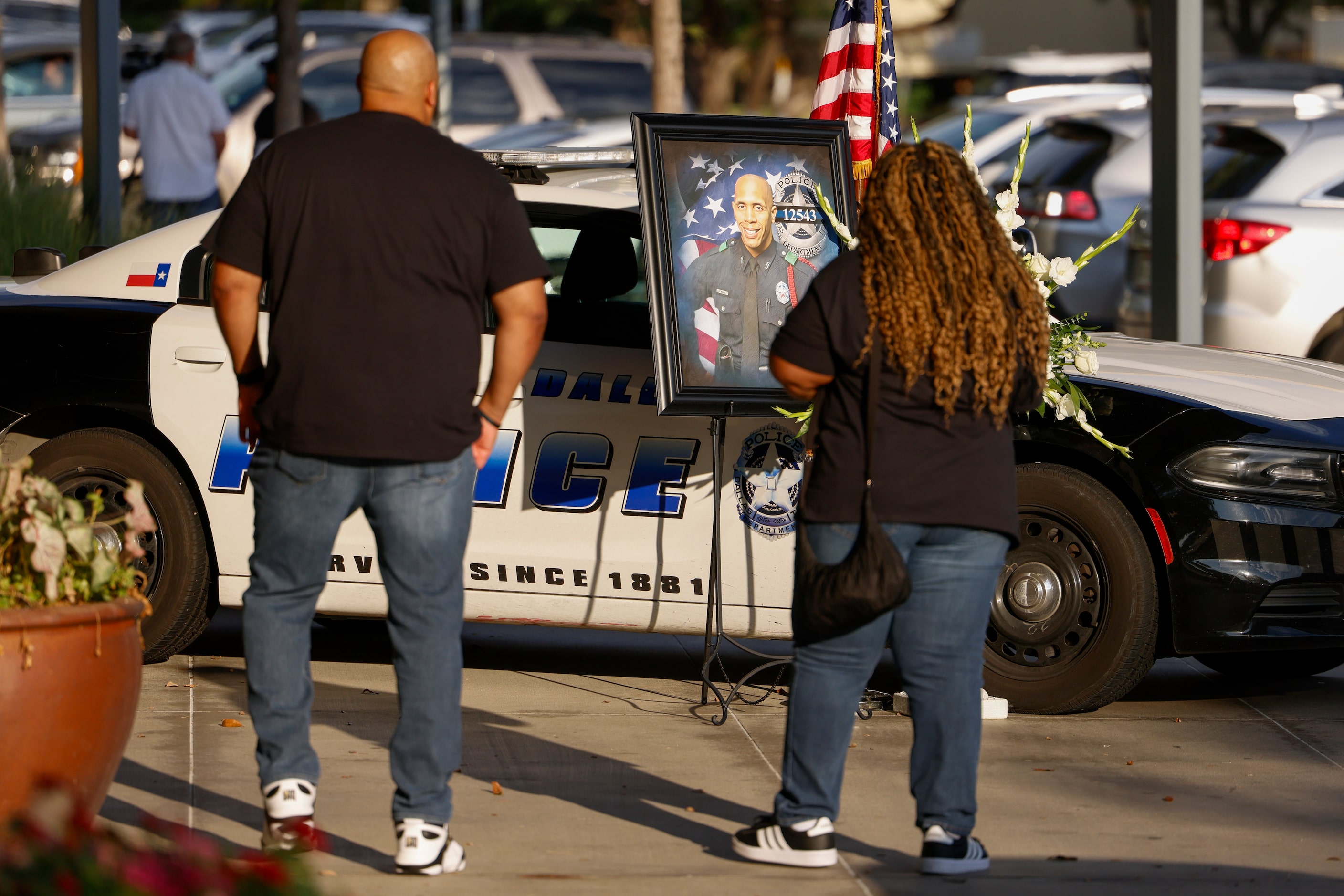 People pause to pay their respects to a memorial for Dallas police Officer Darron Burks...