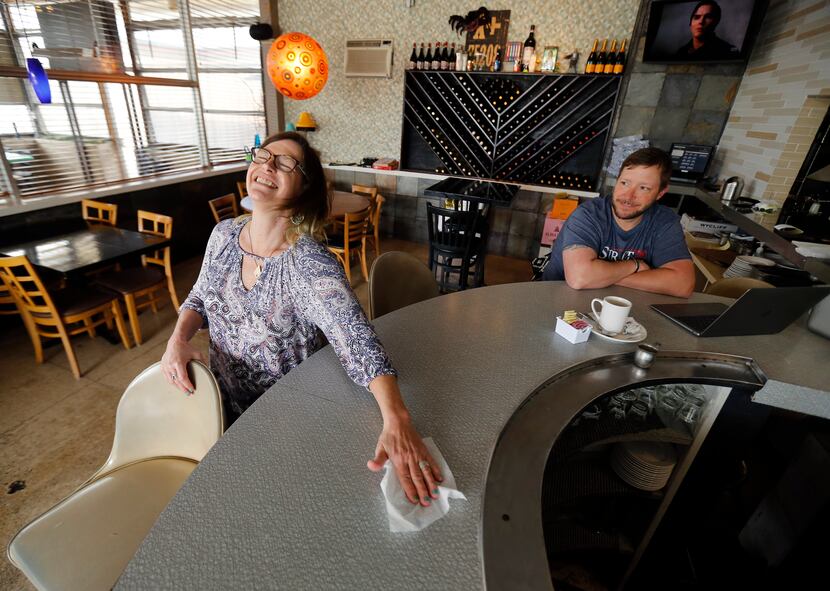 With the music playing, Kari Lynn Scott (left) playfully disinfected the bar on Saturday,...