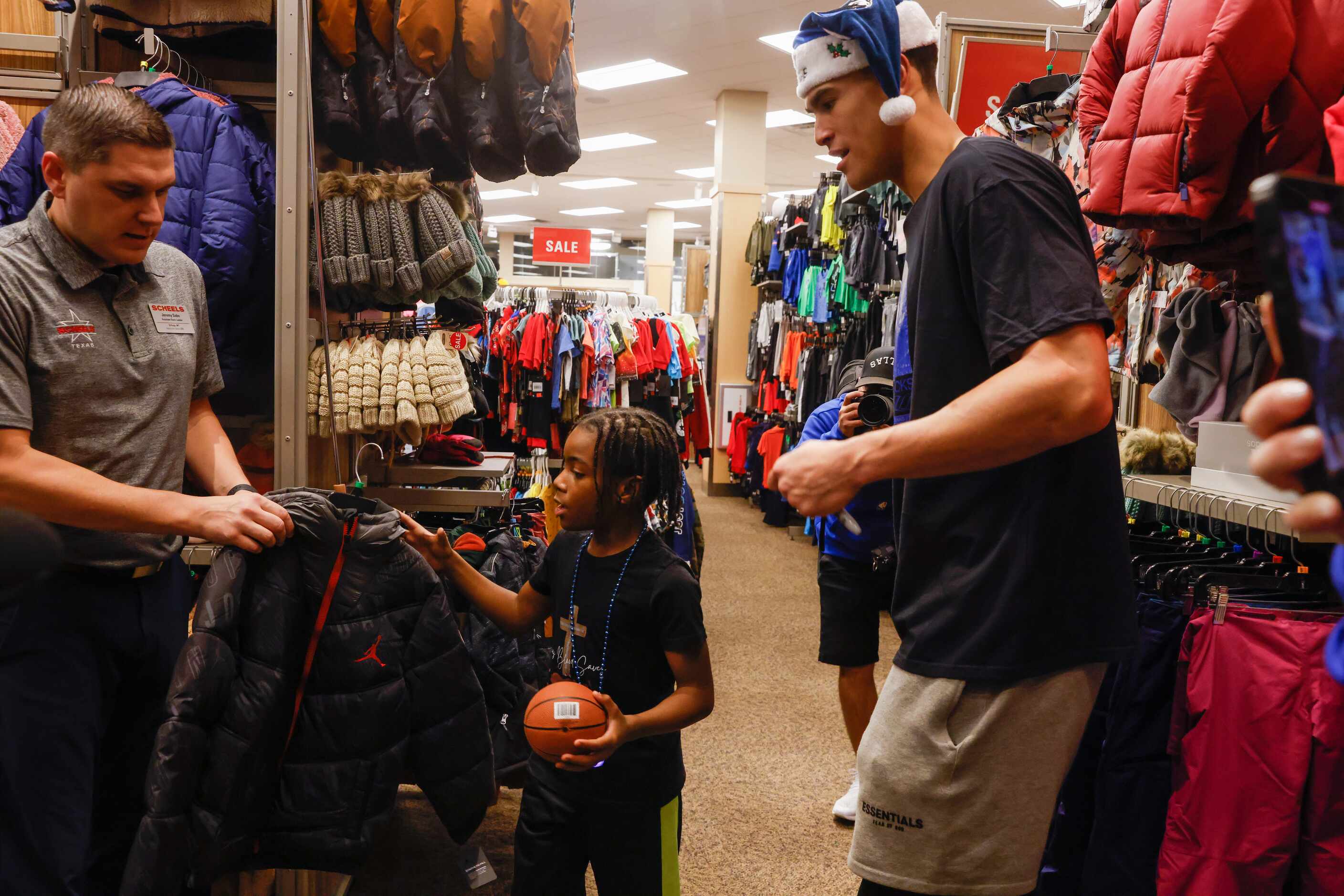 Derrick Givens, Jr. (center), 9, reaches for a jacket to try on while shopping with Dallas...