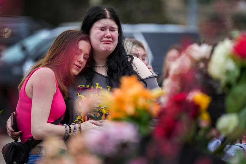 Alexa Keith (center) hugs Brooklyn Deese (left) at a growing memorial outside the mall a day...