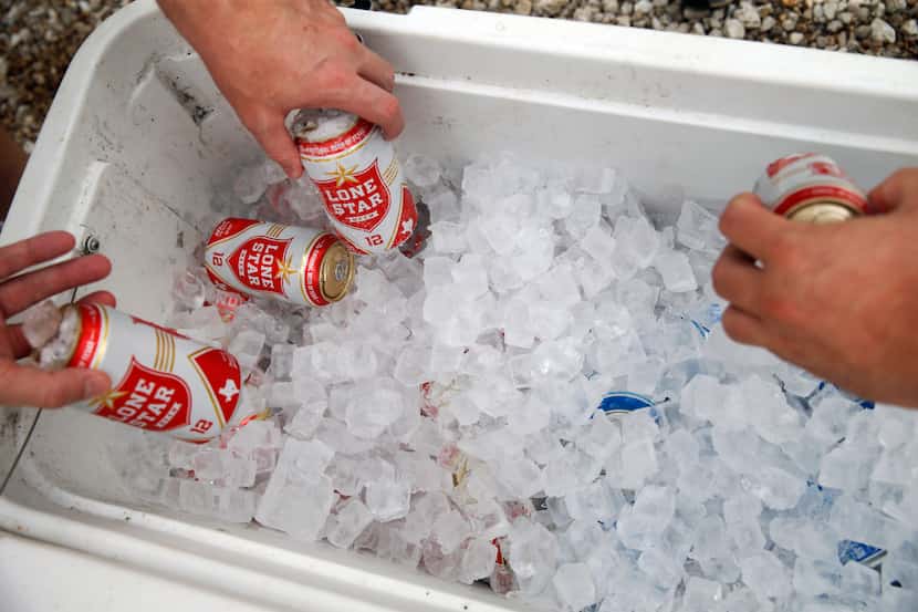People grab free beer to drink as they wait in line at Snow's BBQ.