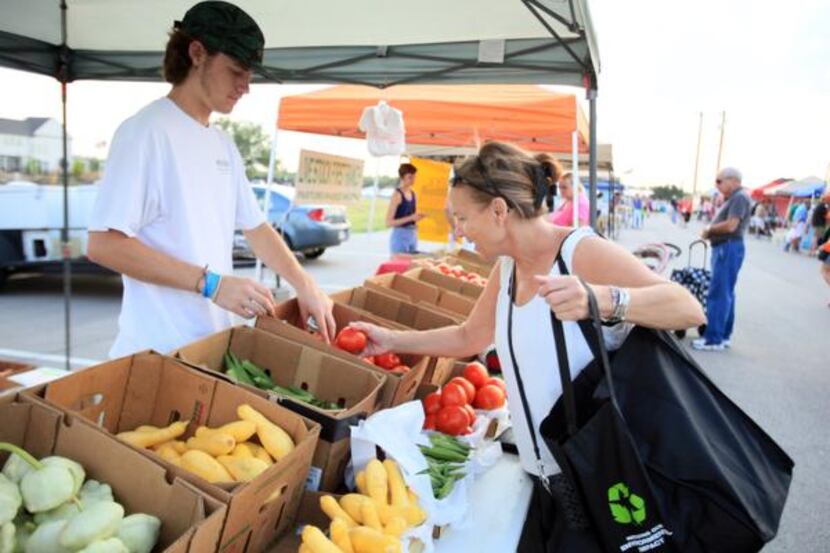 Allison King of Valley Ranch purchases produce from Reid Vandeven, 18, of Fisher Farms, at...