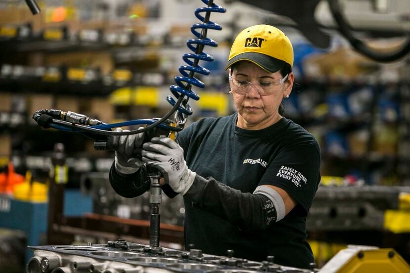 Margarita Cardenas attaches an engine head at Caterpillar's engine manufacturing plant in...