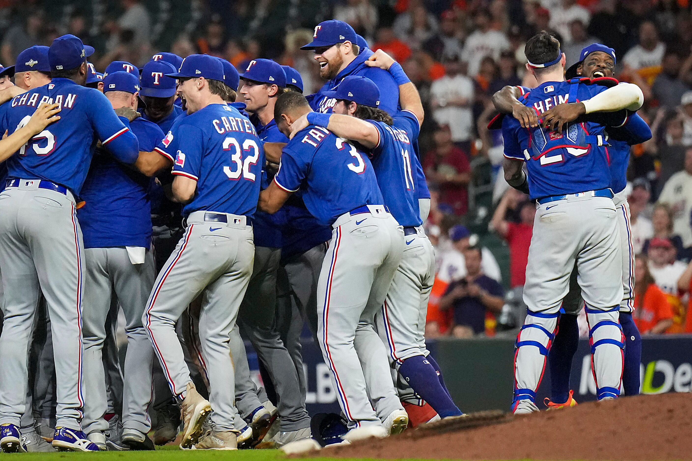 Texas Rangers right fielder Adolis Garcia hugs catcher Jonah Heim (28) at right as player...