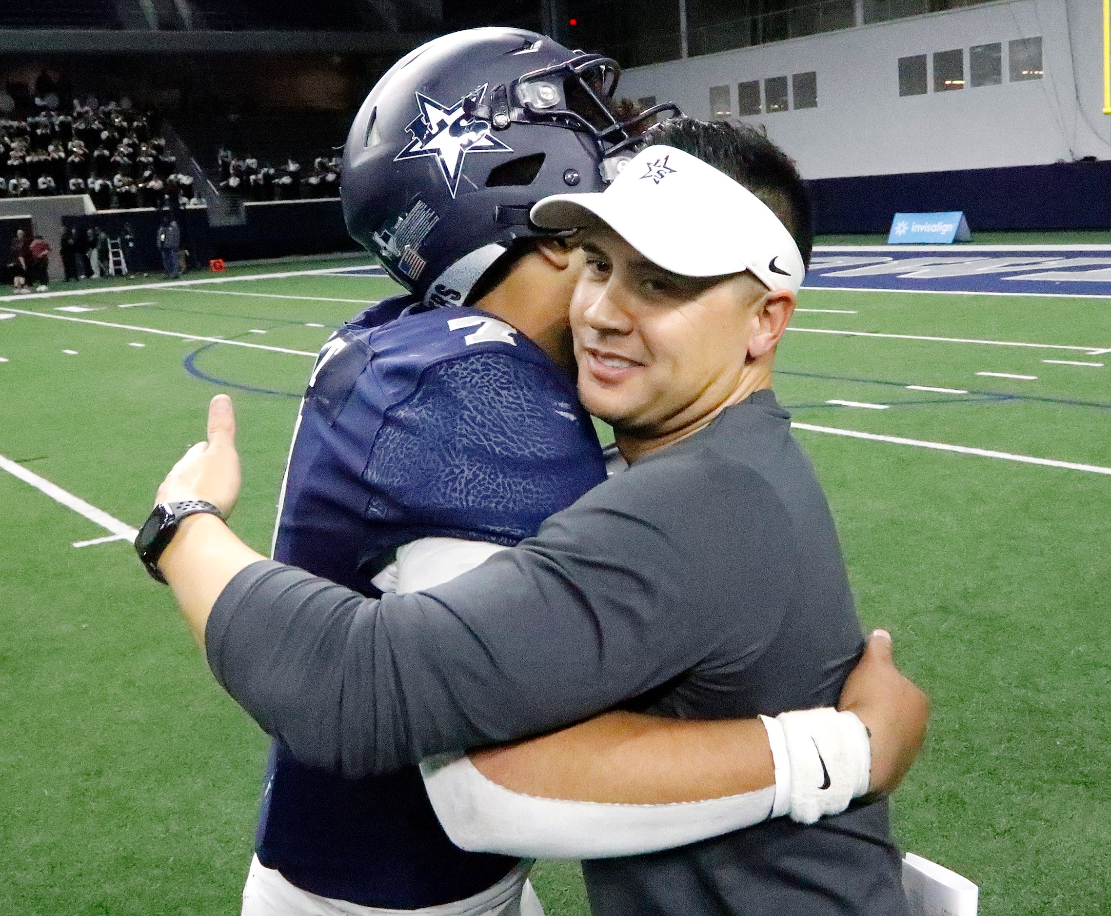 Lone Star High School head coach Jeff Rayburn embraces Lone Star High School quarterback...