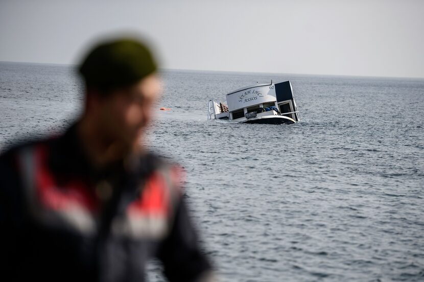 A sinking boat is seen behind a Turkish gendarme off the coast of Canakkale's Bademli...