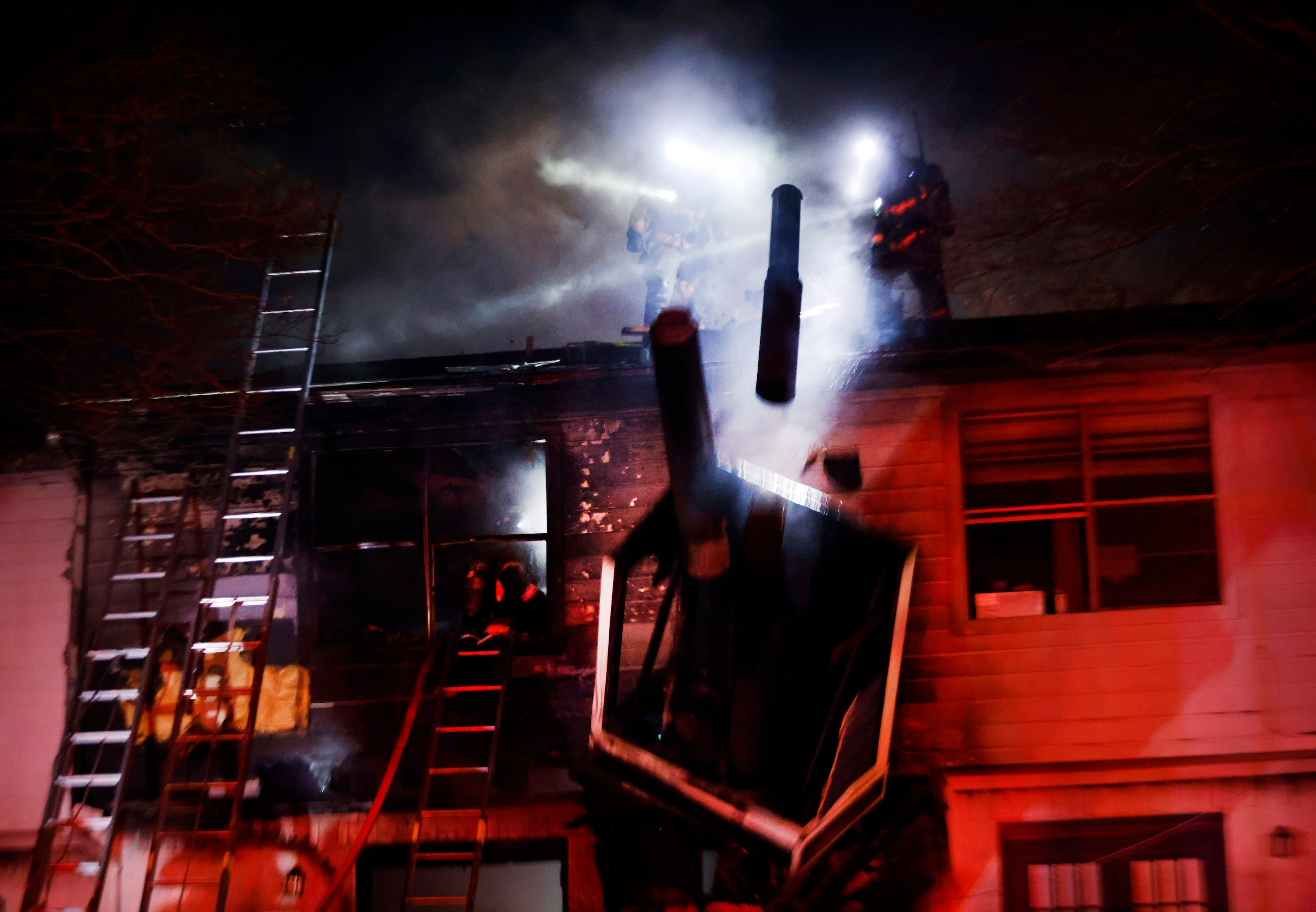 Arlington firefighters push over the chimney and stove pipe as they battled a two-alarm...