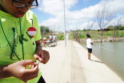 Kyra Dewberry, 16, of Cedar Hill baits her hook while she and her mother fish at Cedar Hill...