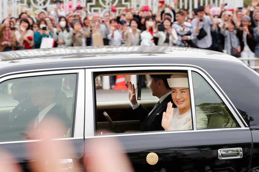 People gather as the car carrying new Emperor Naruhito and Empress Masako passes near state...