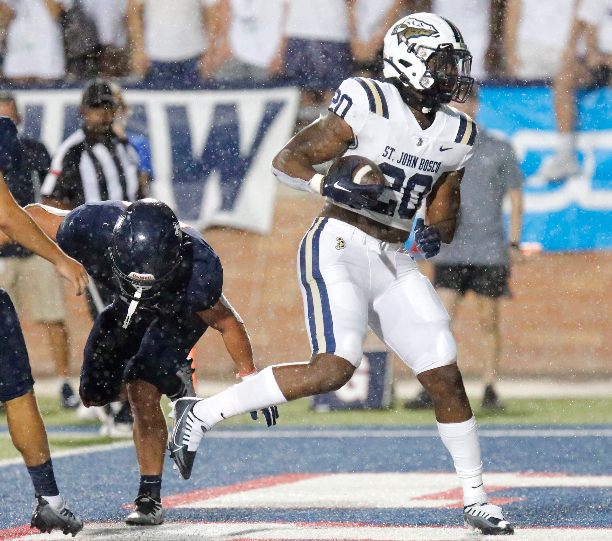 As rain started falling, St. John Bosco High School running back Cameron Jones (20) goes in...