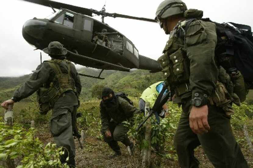 Accompanied by a hooded informant, members of a Colombian police anti-narcotics unit landed...