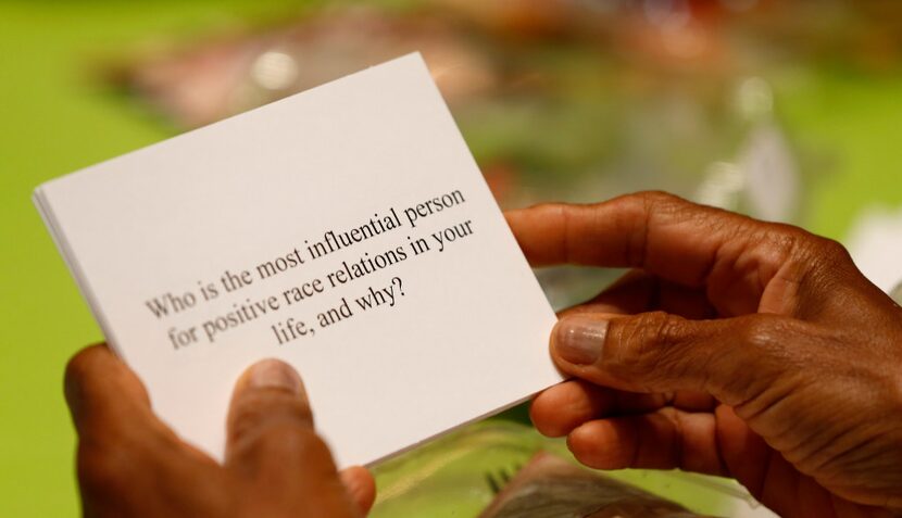 A participant reads a question about race at the dining table during the Together We Dine...