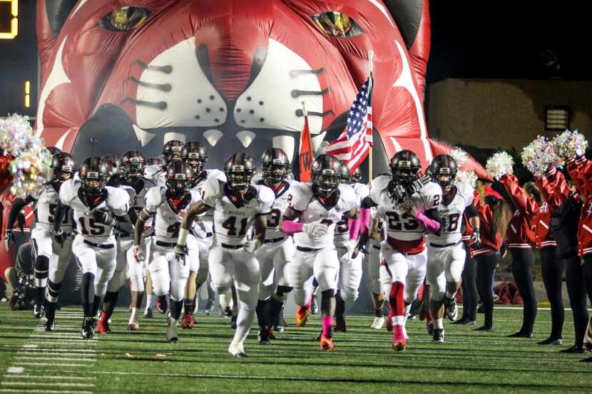 Supported by the cheerleading squad, the Lake Highlands football team runs out onto the...