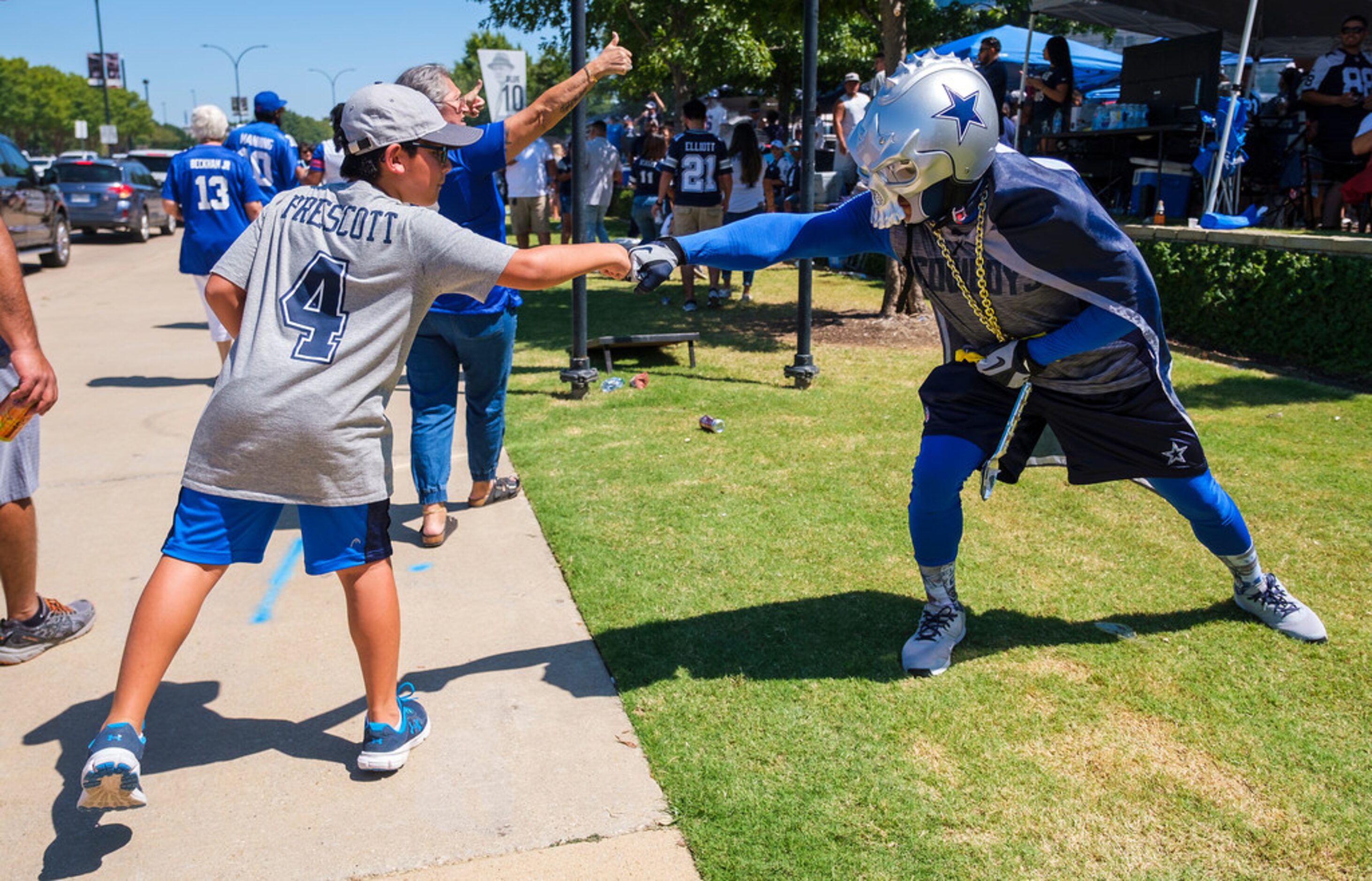 Dallas Cowboys fan Fidel Ramirez (right) first bumps fans arriving at the stadium while...