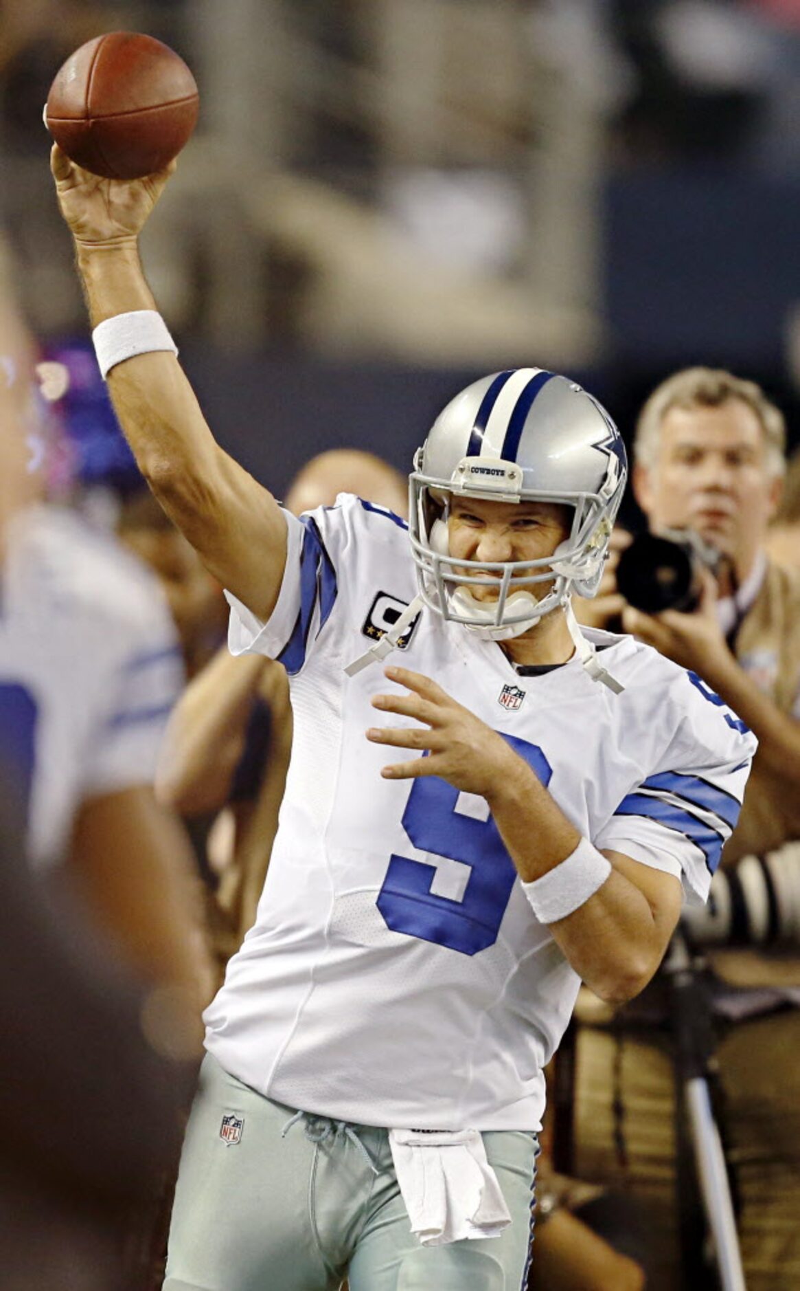 Dallas Cowboys quarterback Tony Romo (9) winces as he tosses the ball on the sidelines...