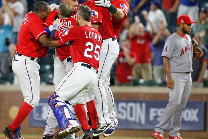 Teammates mob Texas Rangers center fielder Ian Desmond (20) after his ninth-inning single...