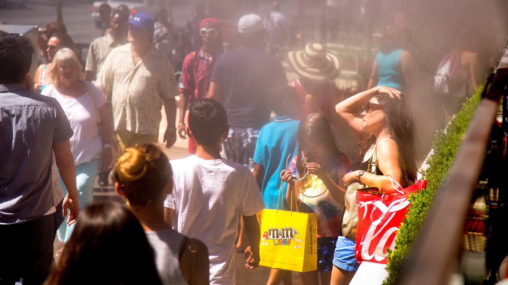 Tourists walk close to misters to keep cool as they walk along The Strip during a heat wave...
