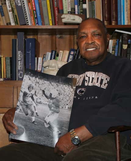 Wallace Triplett III holds a photo of himself carrying the ball while being chased by...