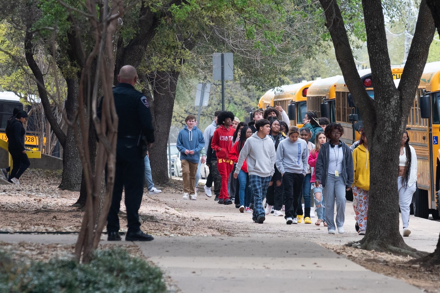 An Arlington Police Officer, left, watches Lamar High School students and faculty as they...