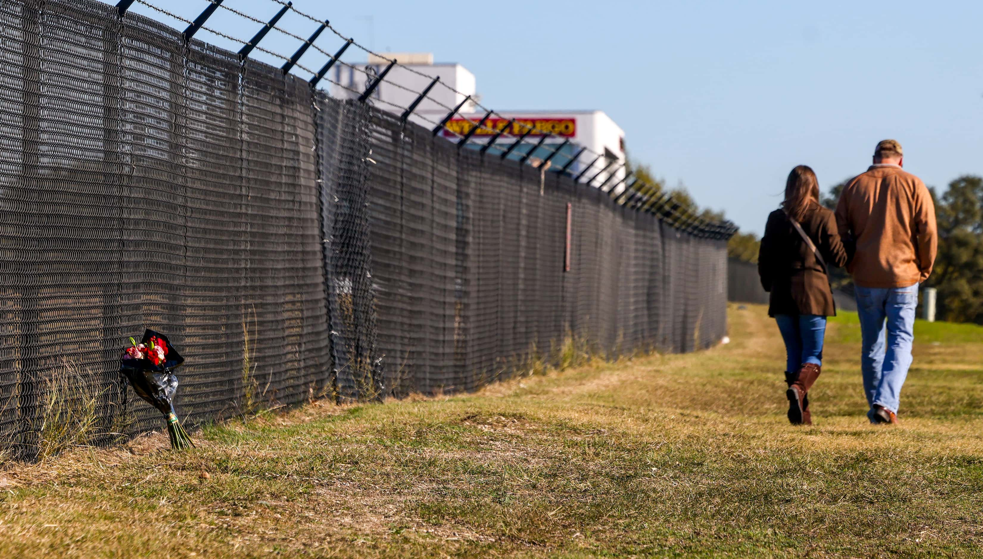 Flowers are left along the fenceline of the Dallas Executive Airport on Sunday, Nov. 13,...