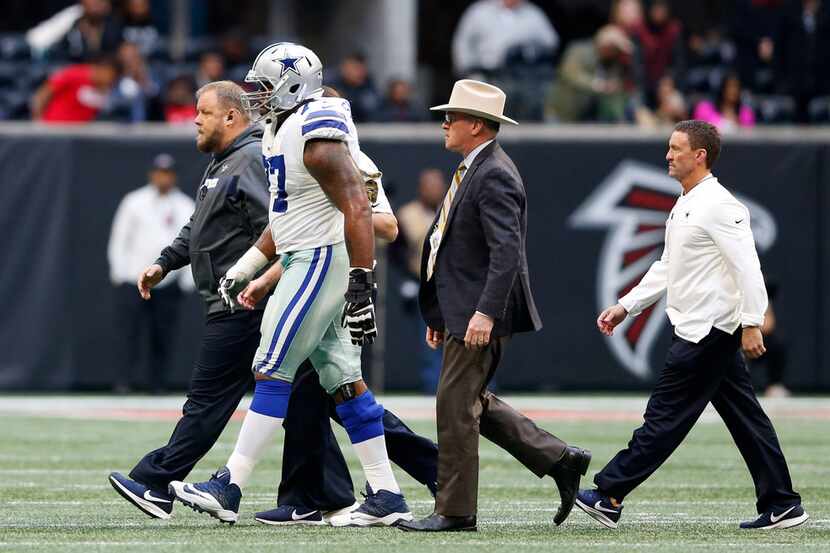 Dallas Cowboys offensive tackle Tyron Smith (77) is walked off the field with Dallas Cowboys...