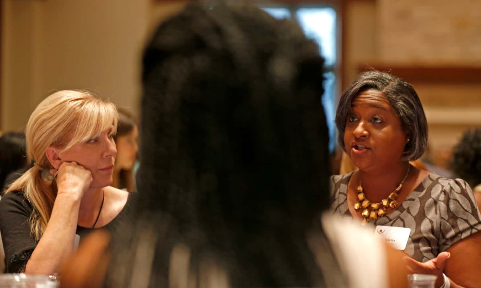 Rachel Ridge (left) watches Rhetta Bowers talk about race at the dining table during the...