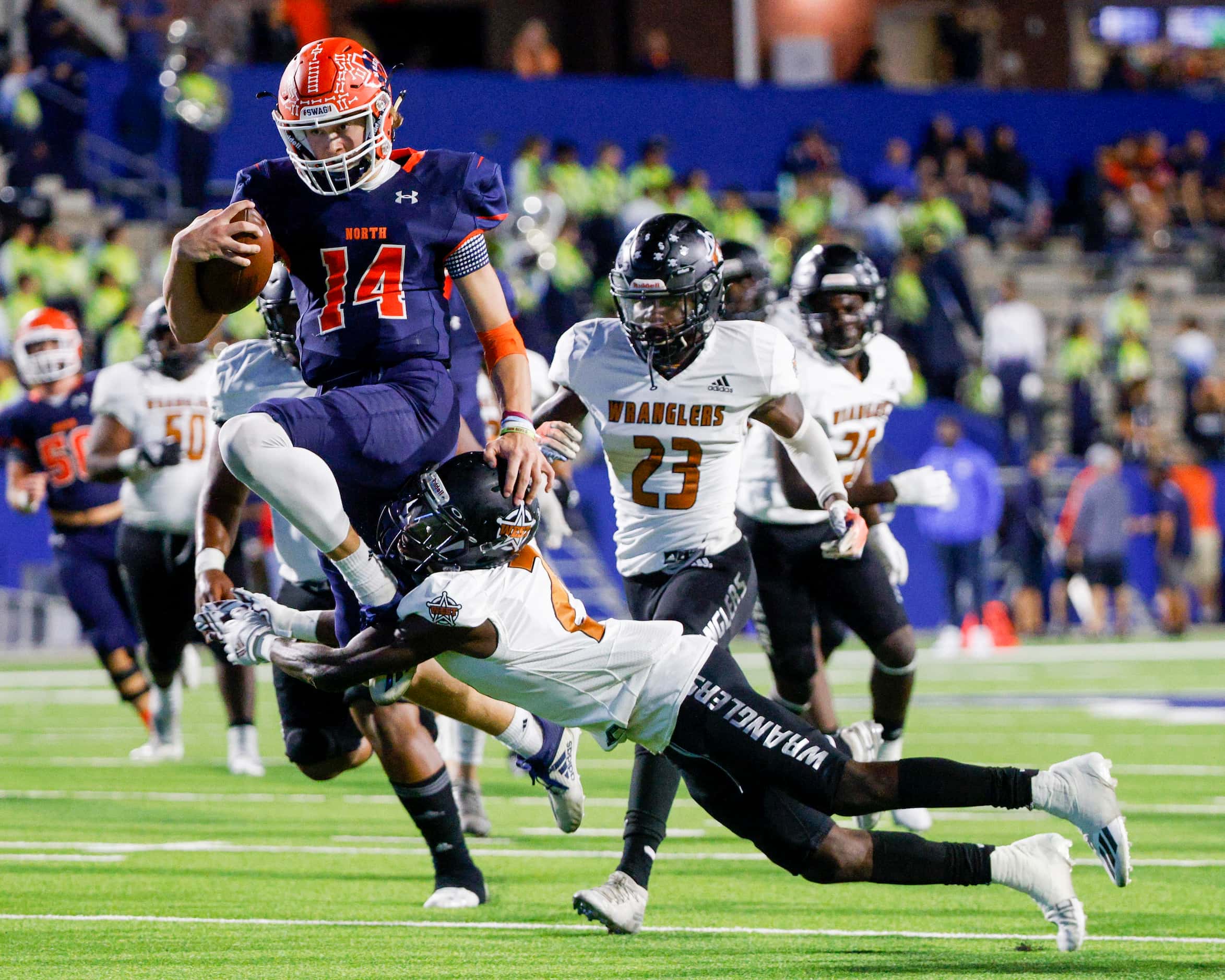 McKinney North quarterback Colin Hitchcock (14) hurdles over the tackle of West Mesquite’s...