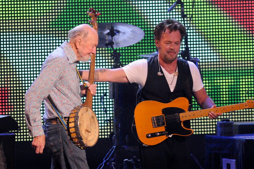 File-This Sept. 21, 2013, file photo shows Pete Seeger, left, being welcomed on stage by...