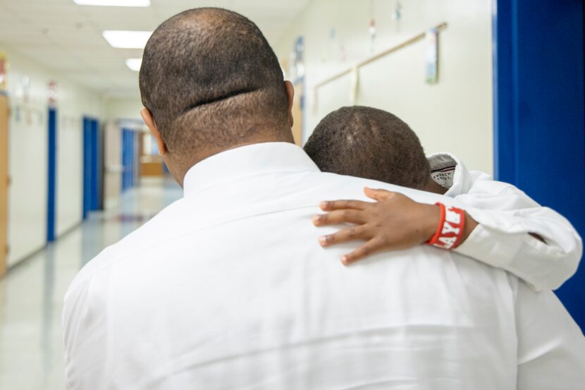 Eric Johnson carries his 5-year-old son, William, as they make their way to his first class...