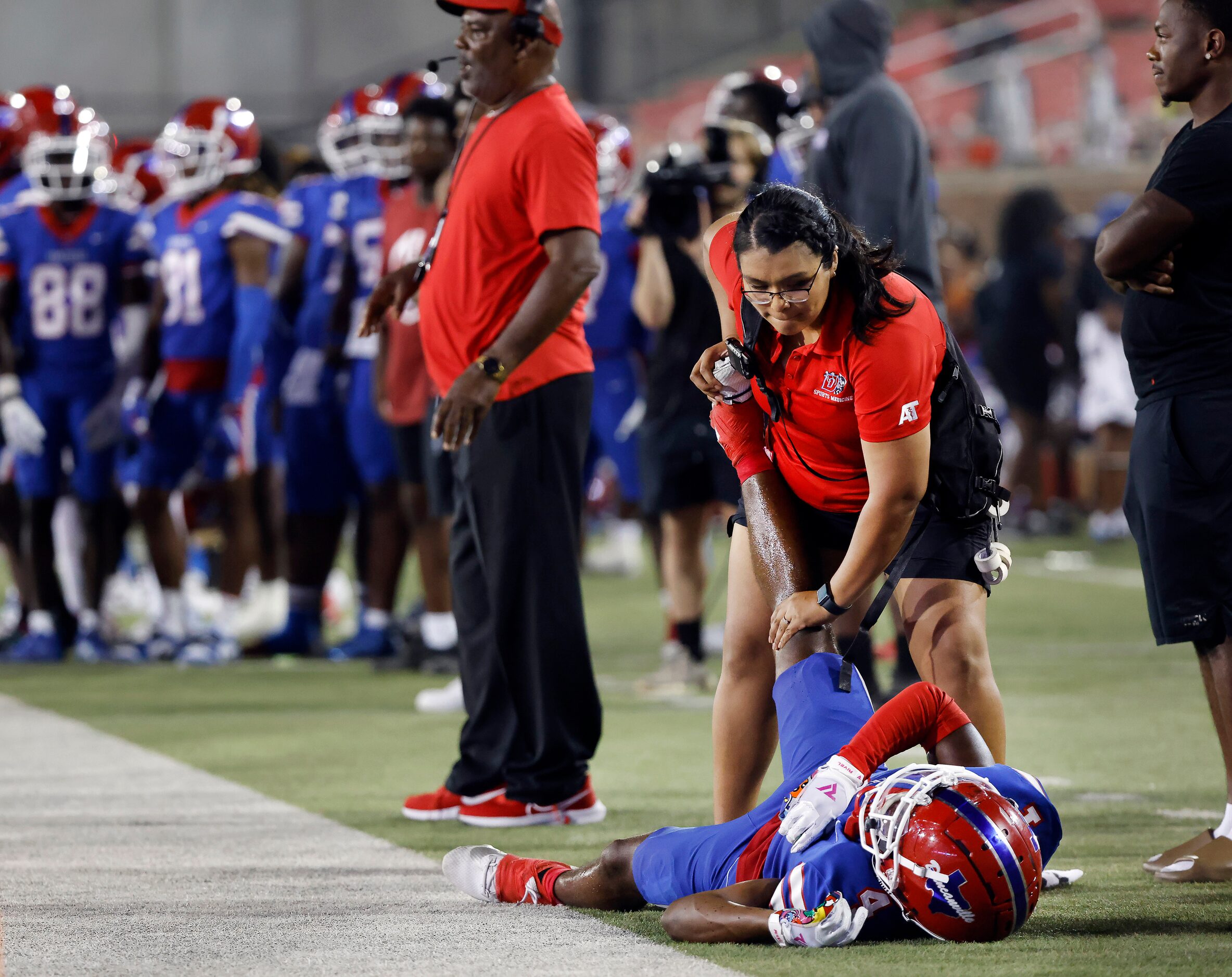 Duncanville wide receiver Ayson Theus (4) has a cramp worked out on the sideline as a South...