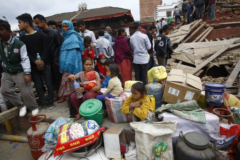 People gather beside damaged buildings in Kathmandu, Nepal, after a 7.8-magnitude earthquake...