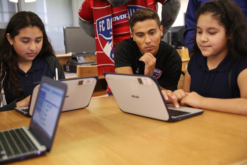 FC Dallas player Aaron Guillen works on a programming activity with seventh-grade students...