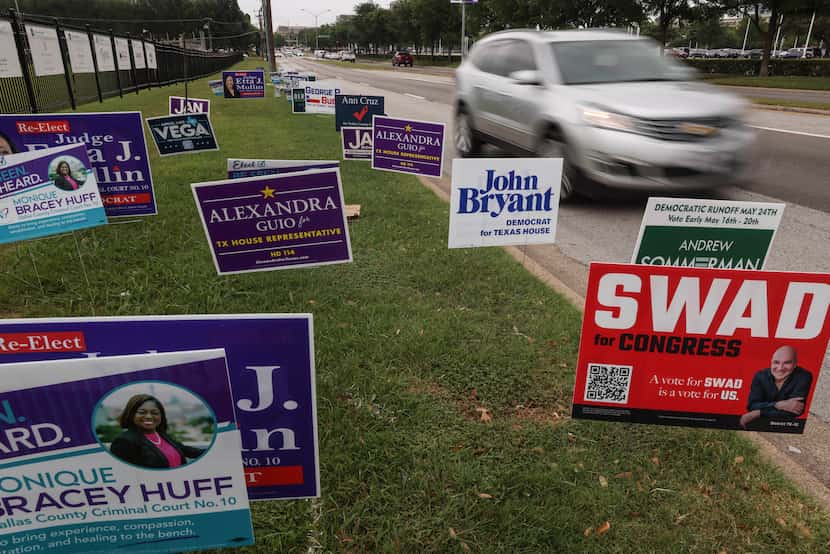 A car drives past signs outside Our Redeemer Lutheran Church, a voting location for Dallas...