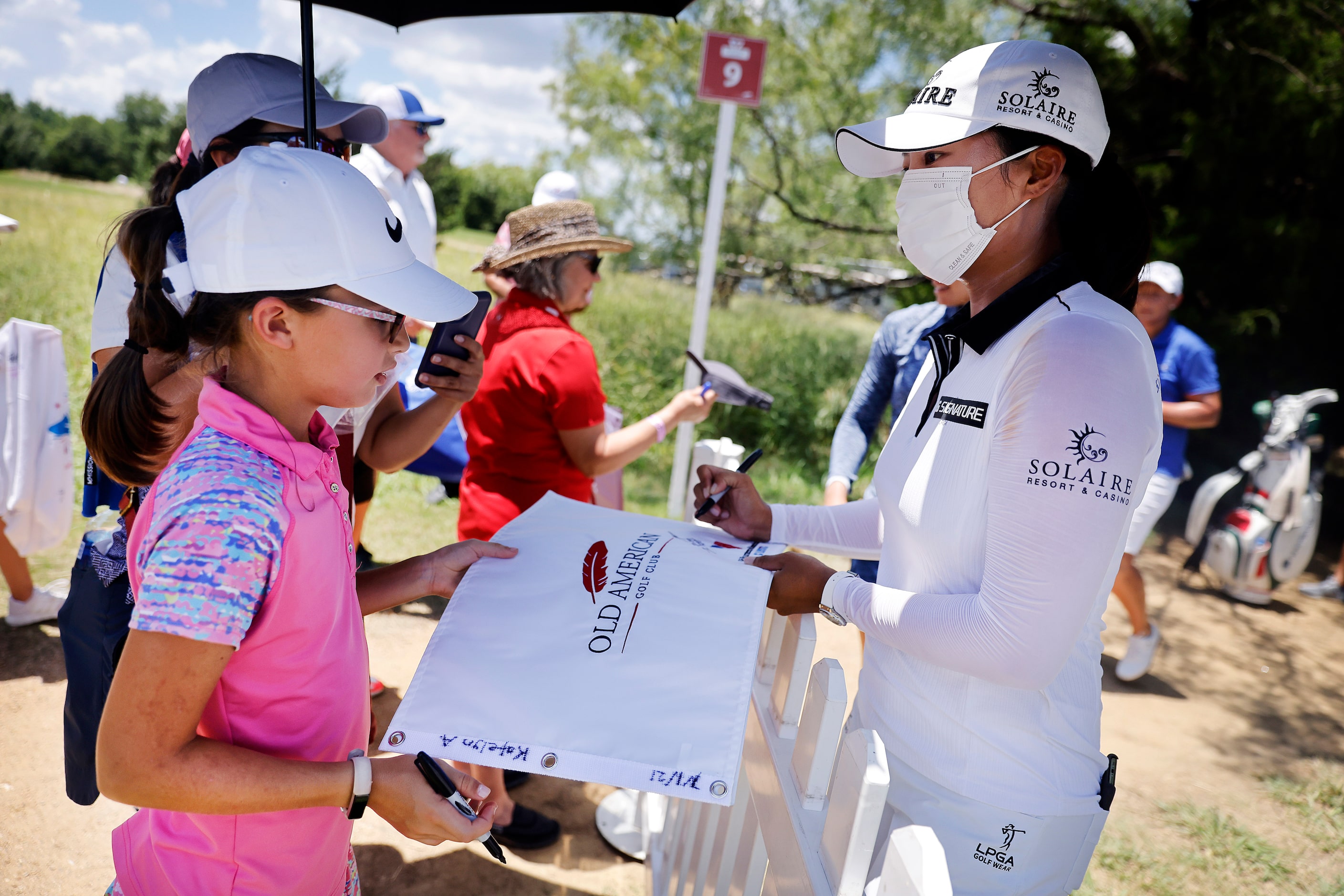 Professional golfer Jin Young Ko (right) signs a pin flag for Katelyn Allen of Montgomery,...