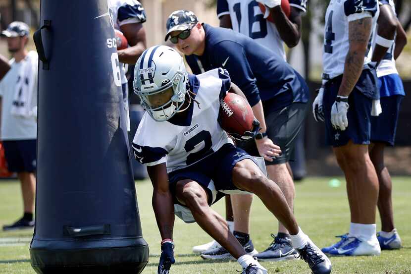 Dallas Cowboys wide receiver KaVontae Turpin digs around a blocking dummy as he carries the...