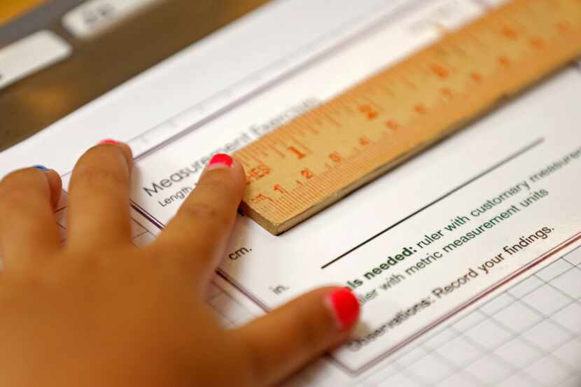 A student uses a ruler while working on her classwork during a Lower Elementary Dual...