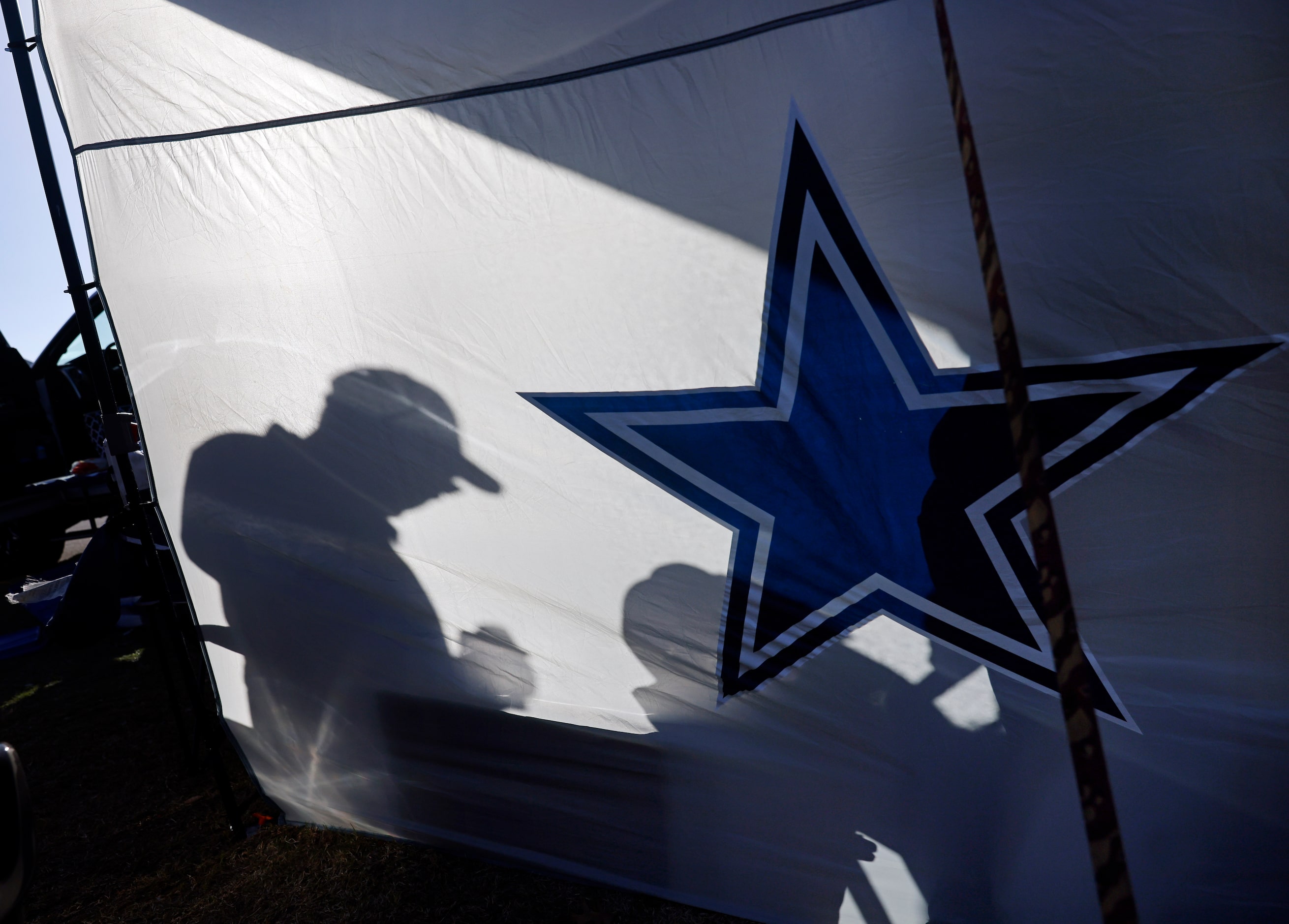 A Dallas Cowboys fan took shelter from the cold wind behind a windbreak at one of the few...