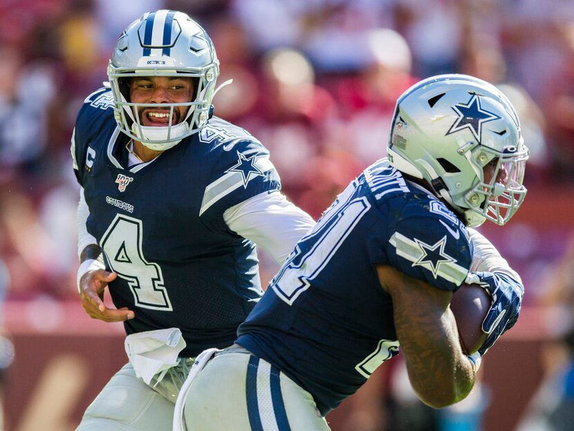 Cowboys quarterback Dak Prescott (4) hands the ball off to running back Ezekiel Elliott (21)...