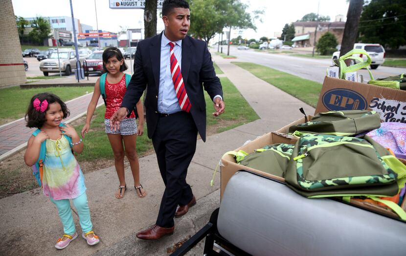 Teacher Adan Gonzalez helps Lluvia Rivera, 5, and her sister, Allison Rivera, 10, pick out...