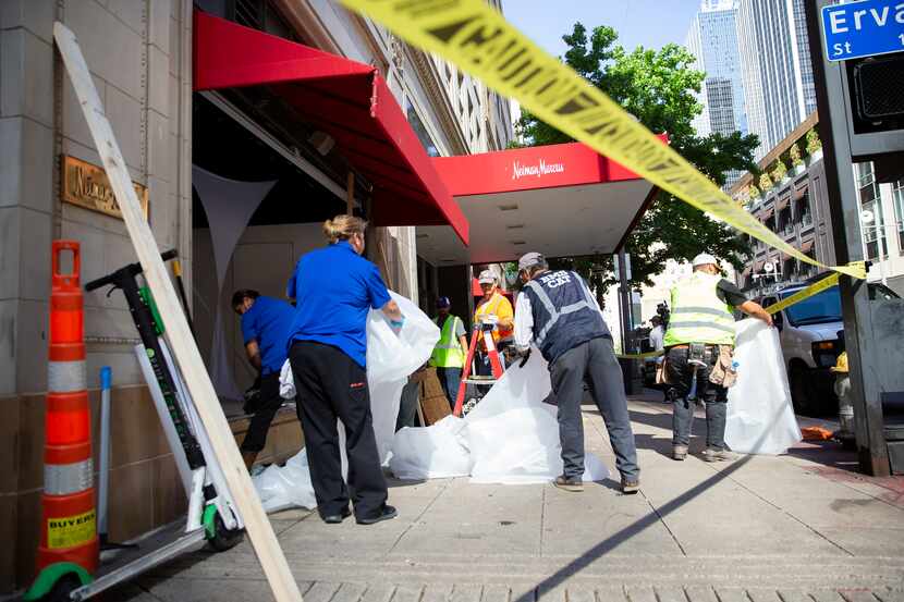 Crews worked to clean up the Neiman Marcus storefront on Main Street on Saturday after it...