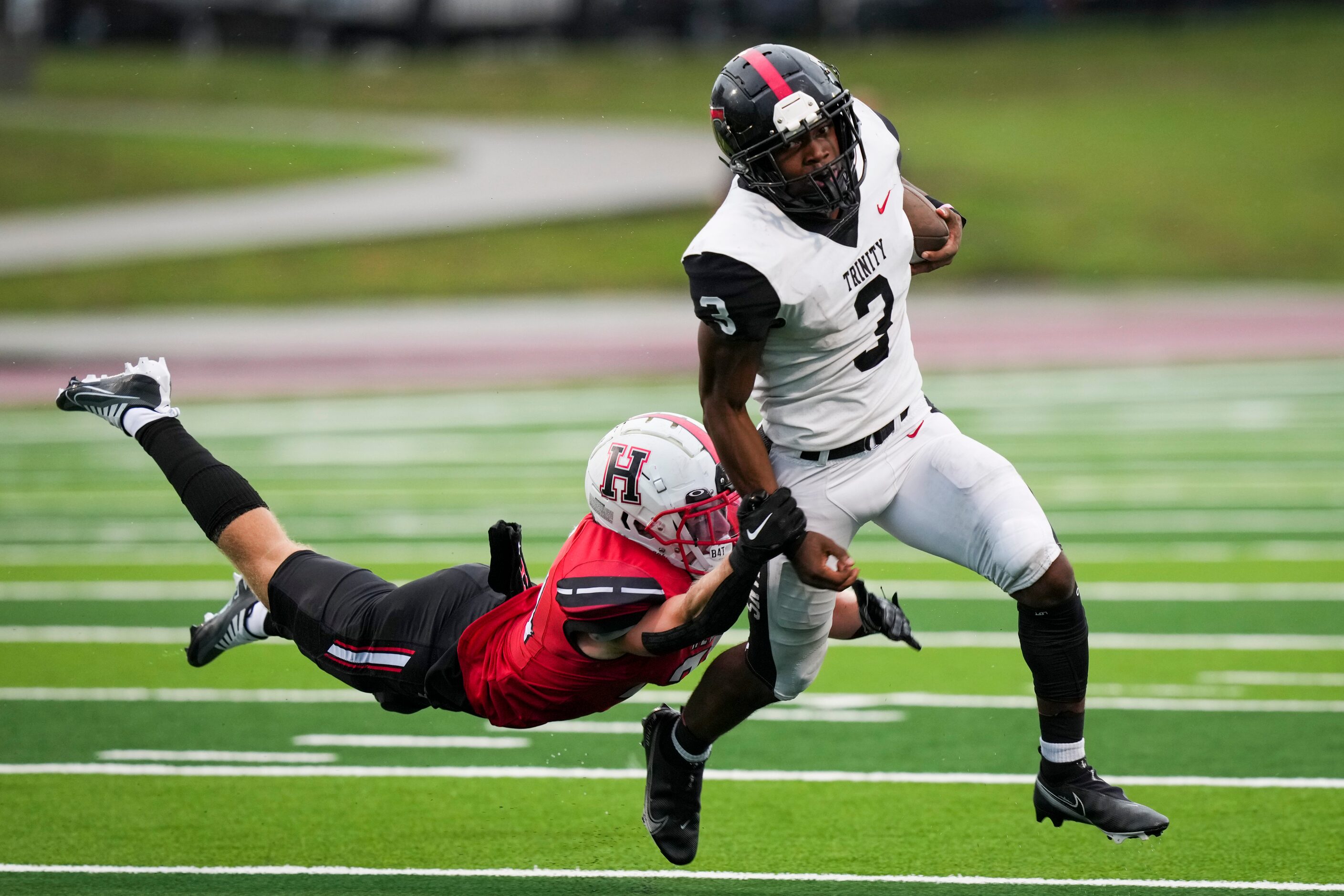 Euless Trinity running back Gary Maddox (3) gets past Rockwall-Heath linebacker Jack Allen...