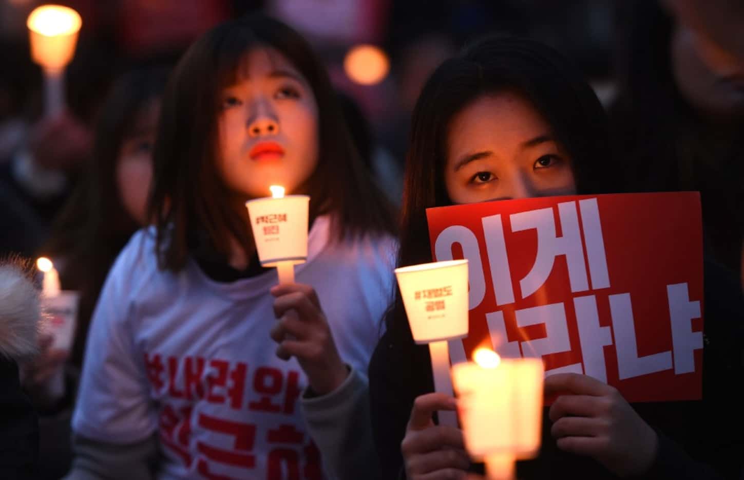 Protesters hold candles and banners calling for the resignation of South Korea's President...