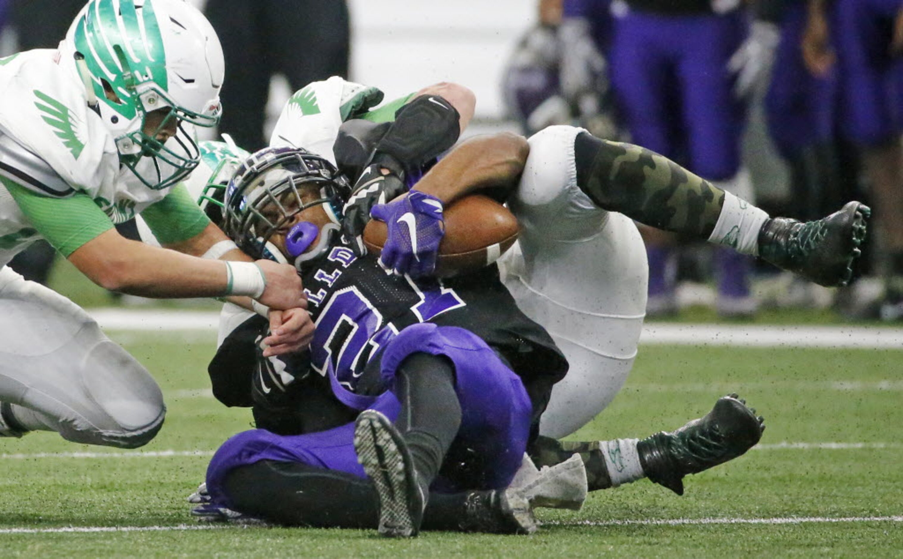 Everman running back Kierre Crossley (21) is brought down by a pair of Lake Dallas defenders...