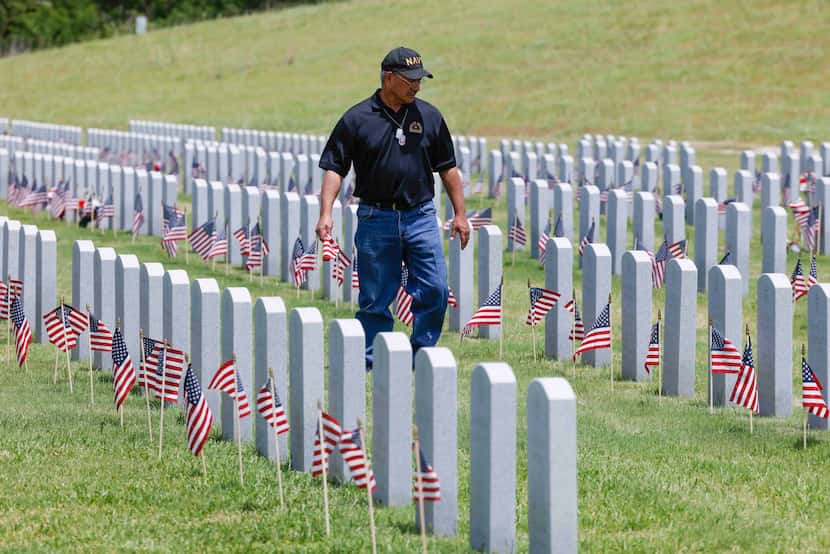 Rick Zamarripa walks down the aisle to place a flag on a grave for a friend on Memorial Day,...